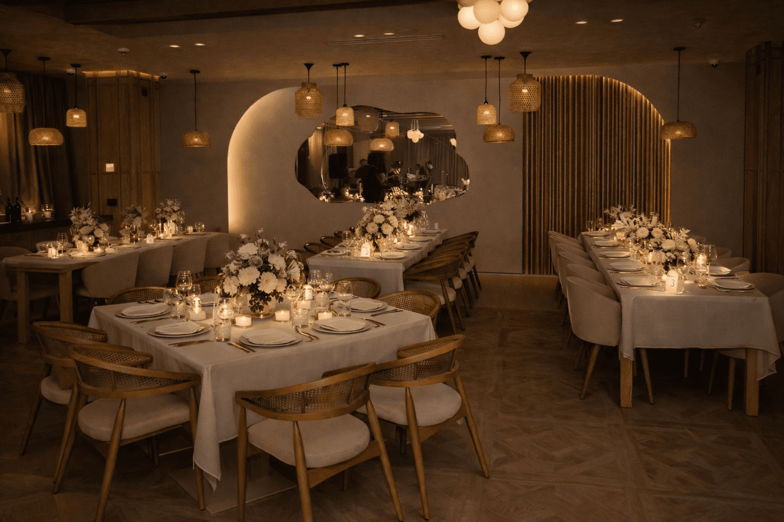 Sophisticated restaurant interior featuring tables set with white flowers, candles, and warm pendant lights.