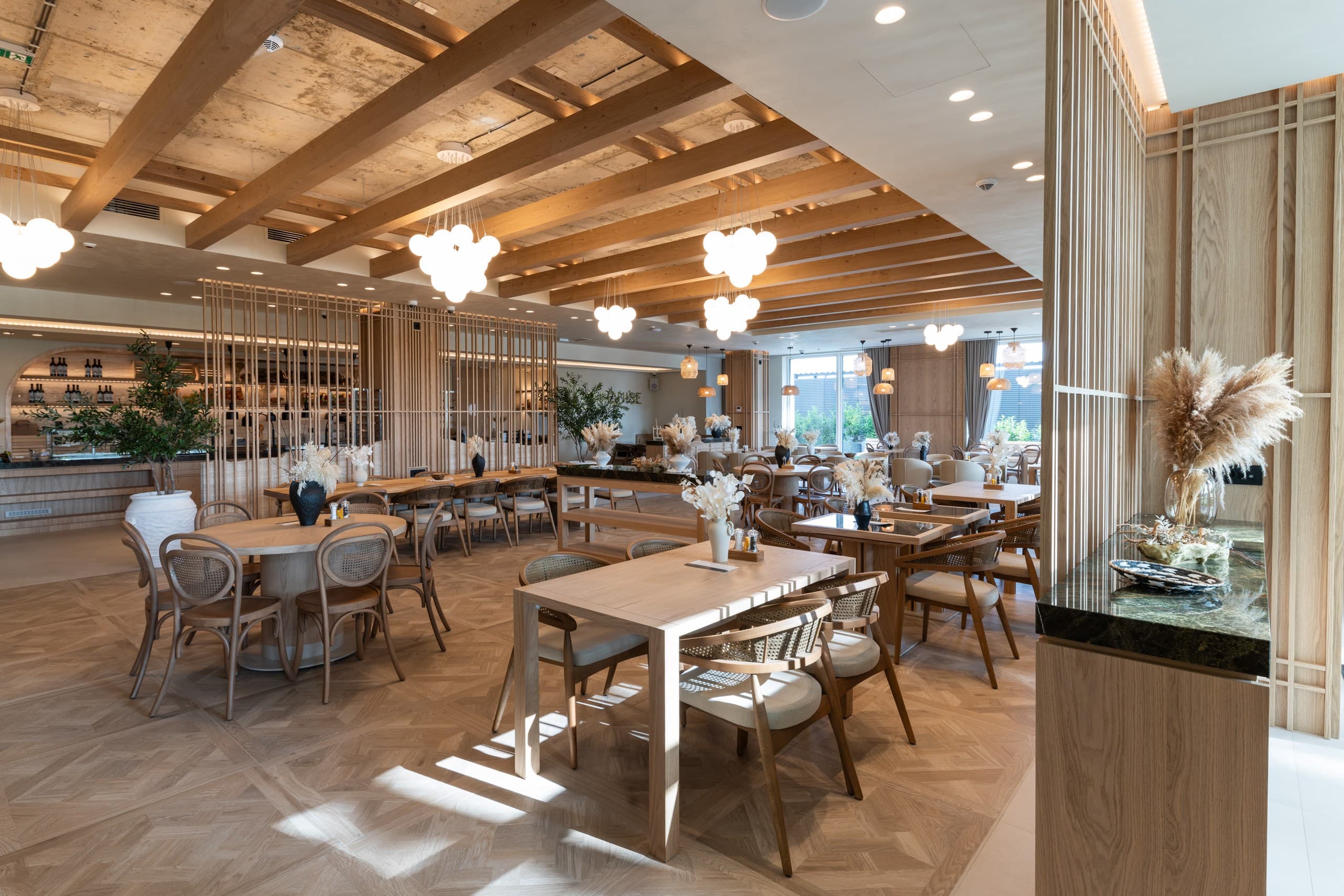 Modern restaurant featuring light wood furniture, exposed ceiling beams, and unique white globe pendant lights.