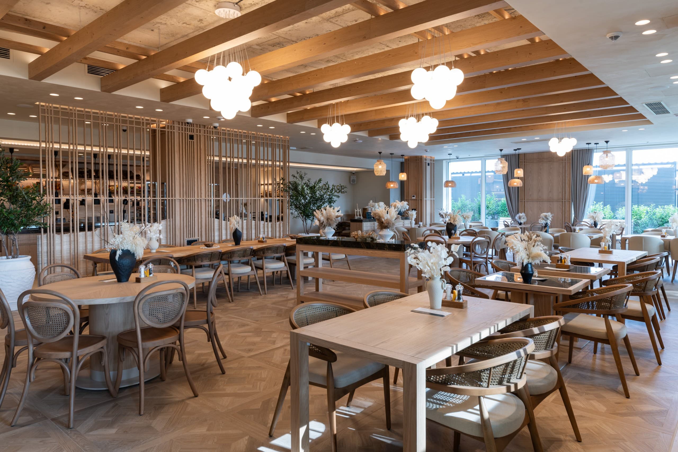 Modern restaurant interior with light wood furniture, exposed beams, and cloud-like pendant light fixtures.