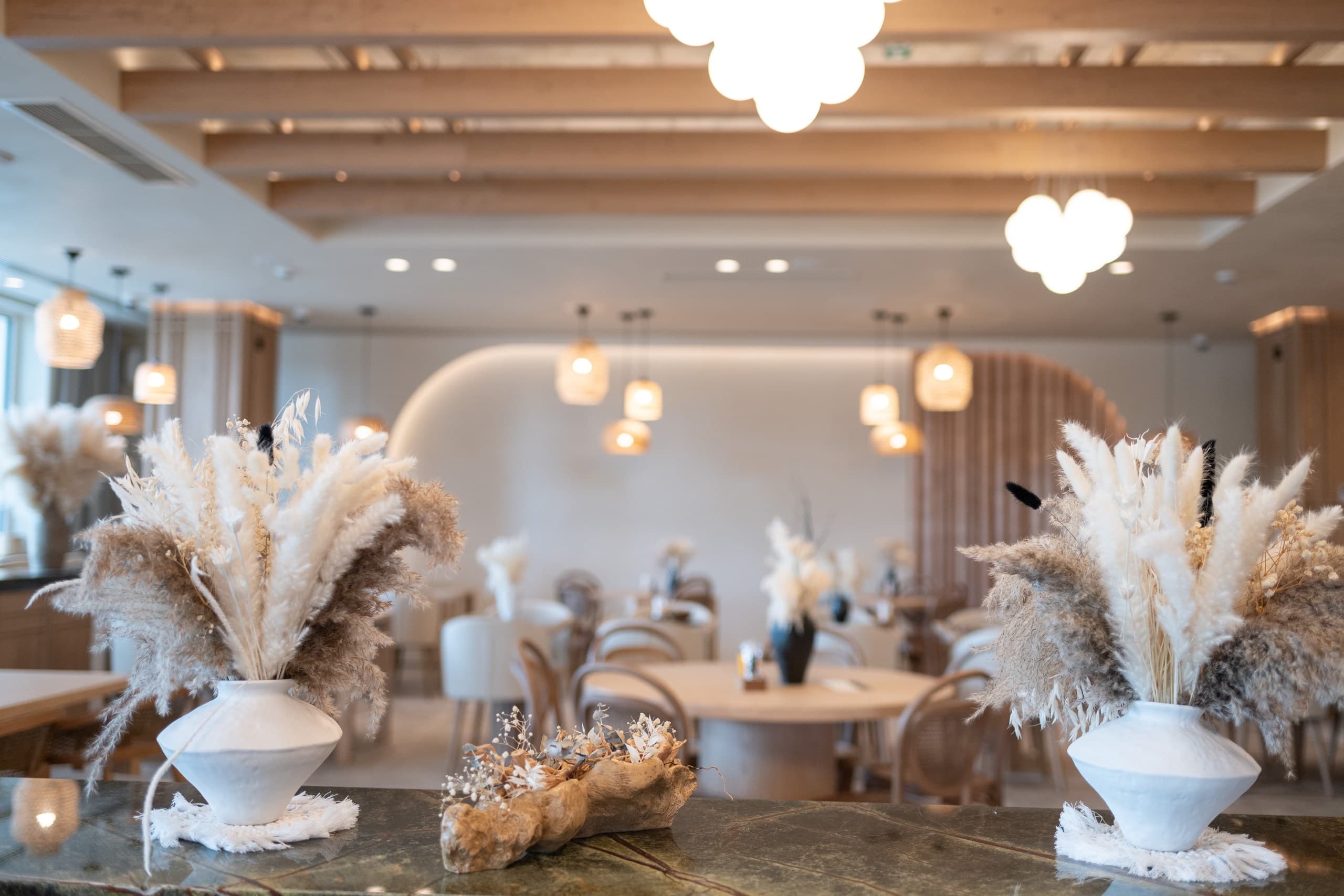 Modern restaurant interior with dried pampas grass in white vases on a marble counter.