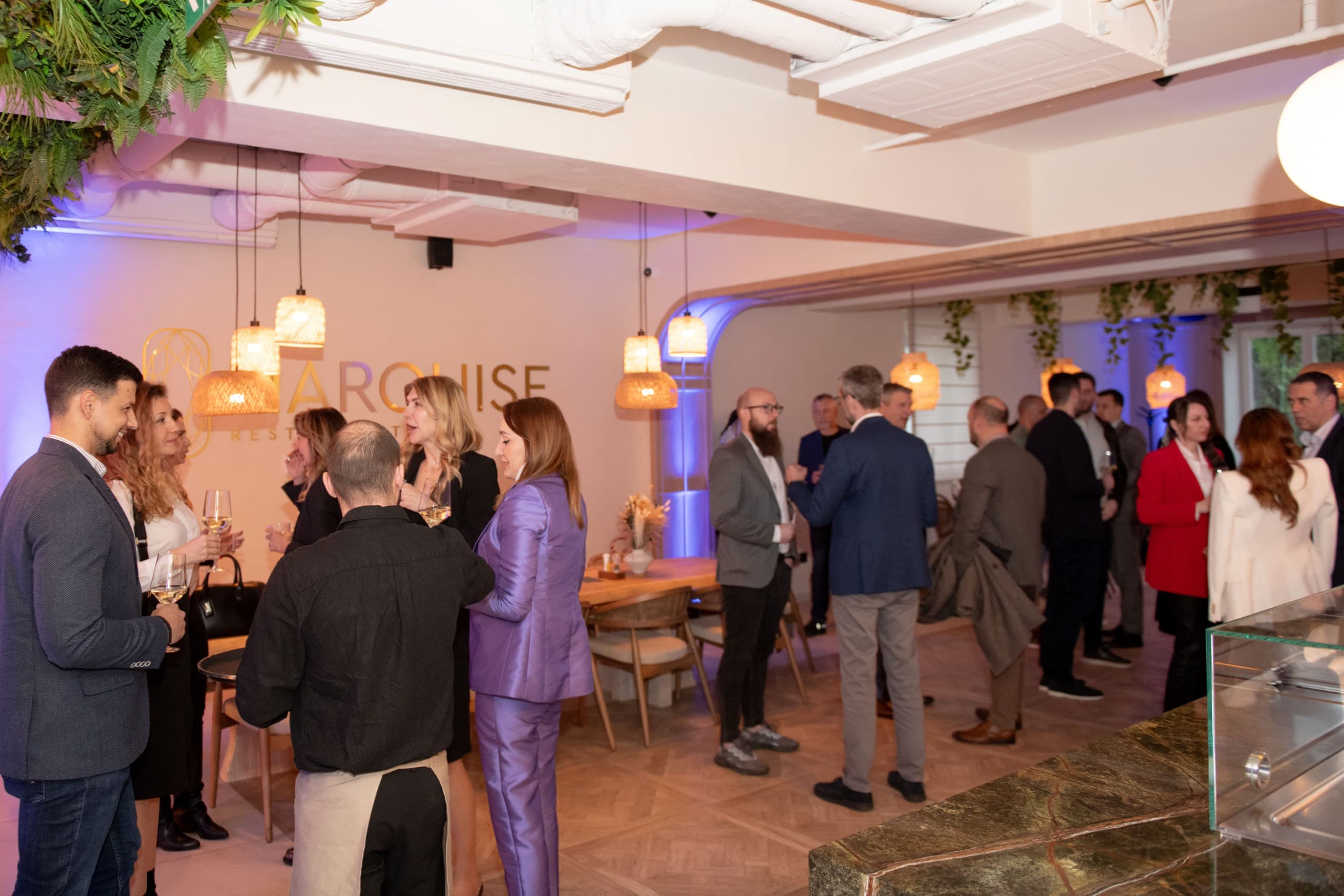 Guests in business attire socializing and drinking wine at a modern indoor networking event.