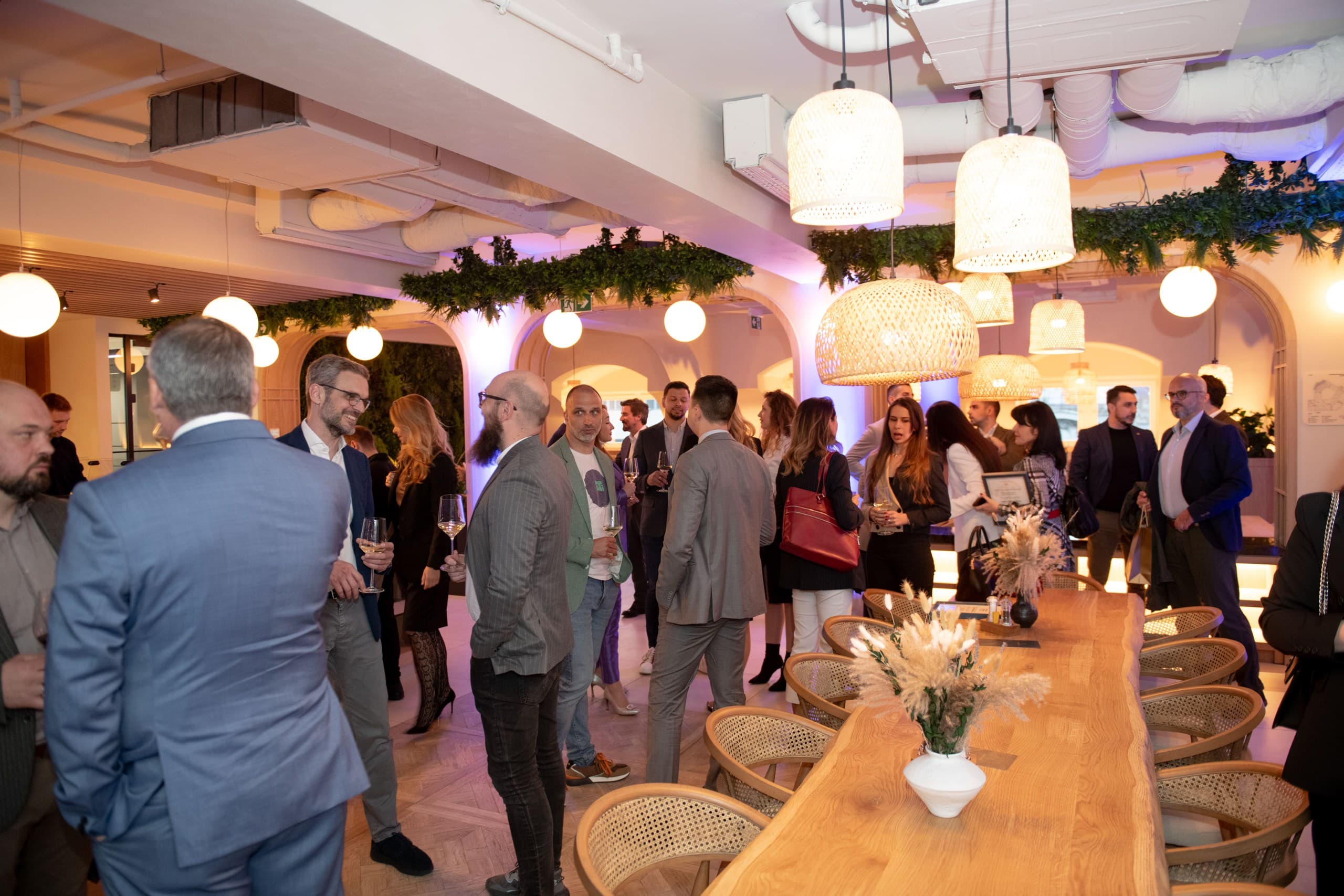Professionals networking and socializing at a modern indoor event with warm, inviting lighting.
